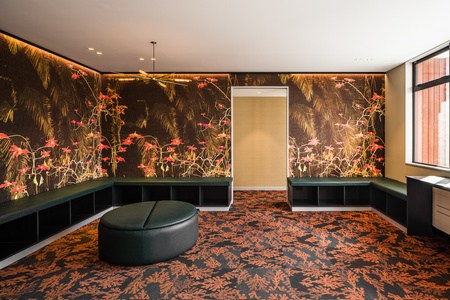 Flow's waiting room wrapped in a dark botanical wallpaper with green bench seating